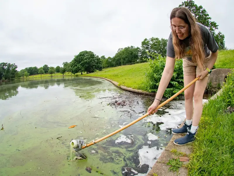 A student scoops water out of a lake