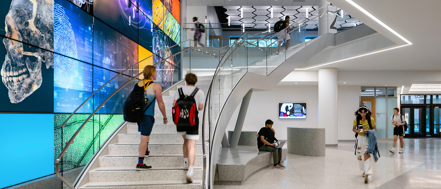 Students walk up the stairs between the first and second floors of the STEM Building