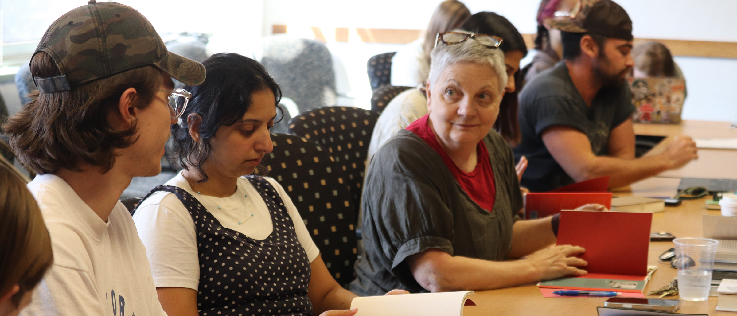 A group of MFA students and faculty sit at a table reading