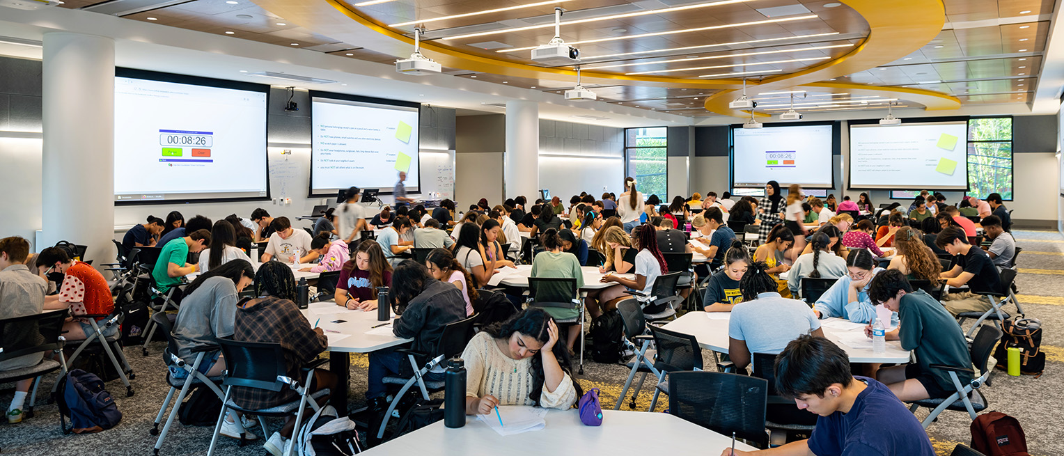 Students work at desks in a large classroom in the STEM Building