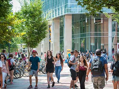 a crowd of students walking around outside of cabell library at v.c.u. on a sunny day