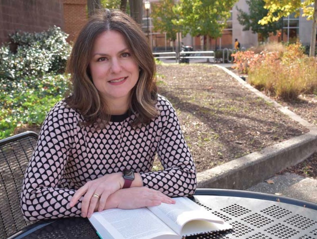 Mary Caton Lingold sitting at a picnic table with a book open in front of her