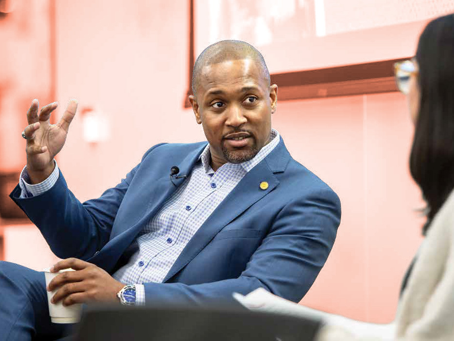 Aaron Gilchrist sitting and speaking to a woman to the right of him