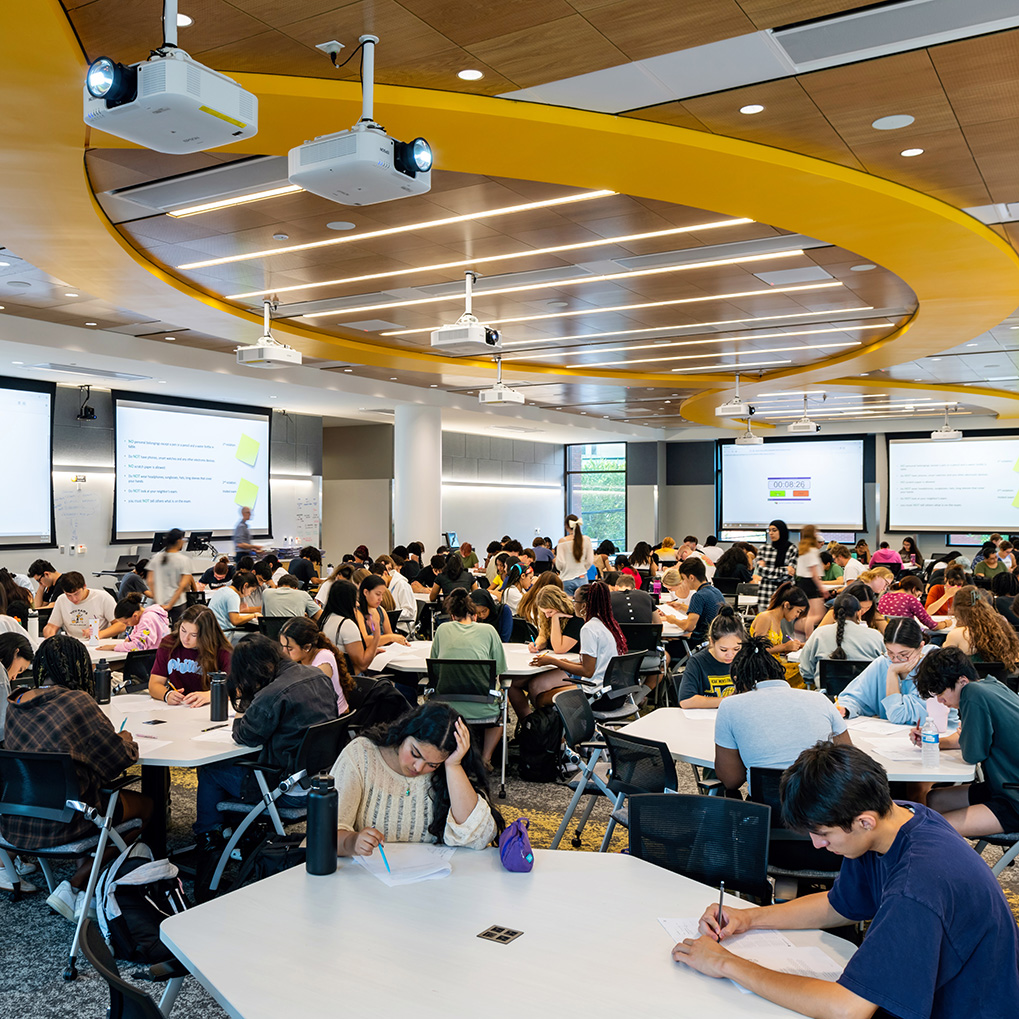 Students site at tables inside the STEM building