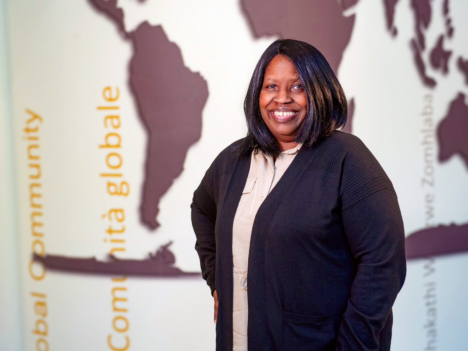 Felicia Fowler stands in front of a world map mural