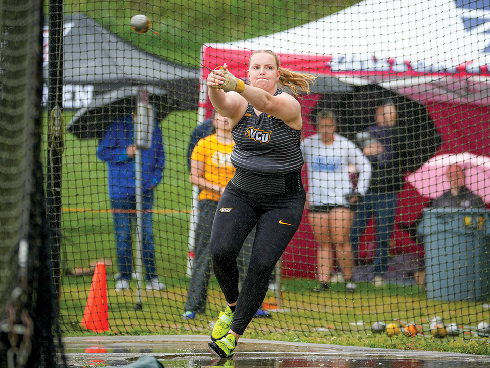 Gudrun Hallgrimsdottir throws a hammer while onlookers watch from behind a net