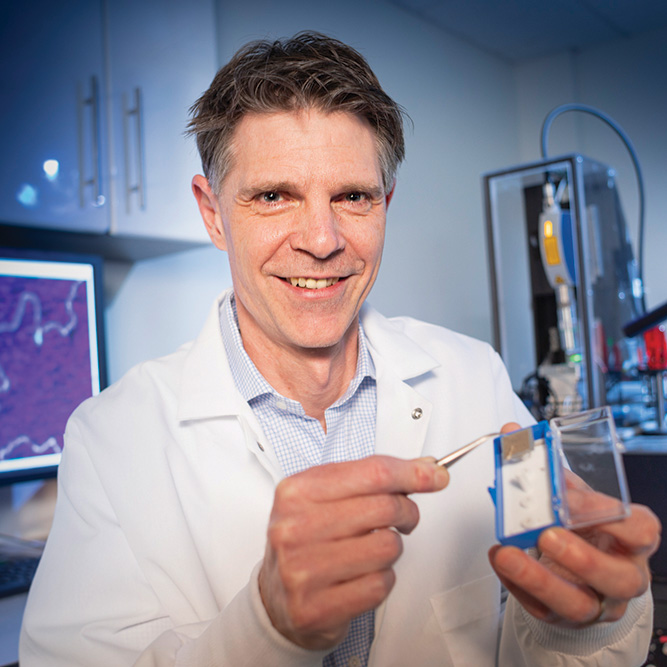 Jason Reed in a lab holding up a specimen