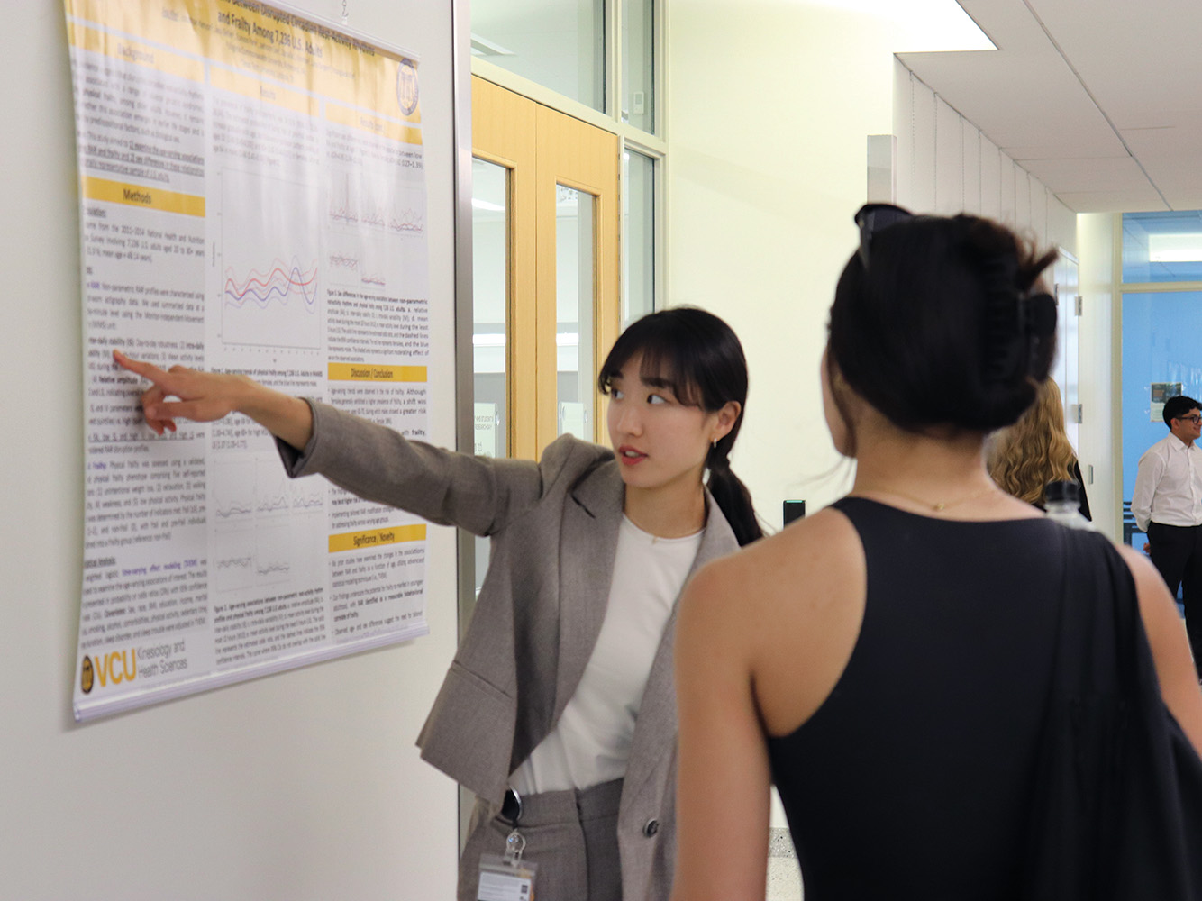 A woman points to a research poster hanging on the wall
