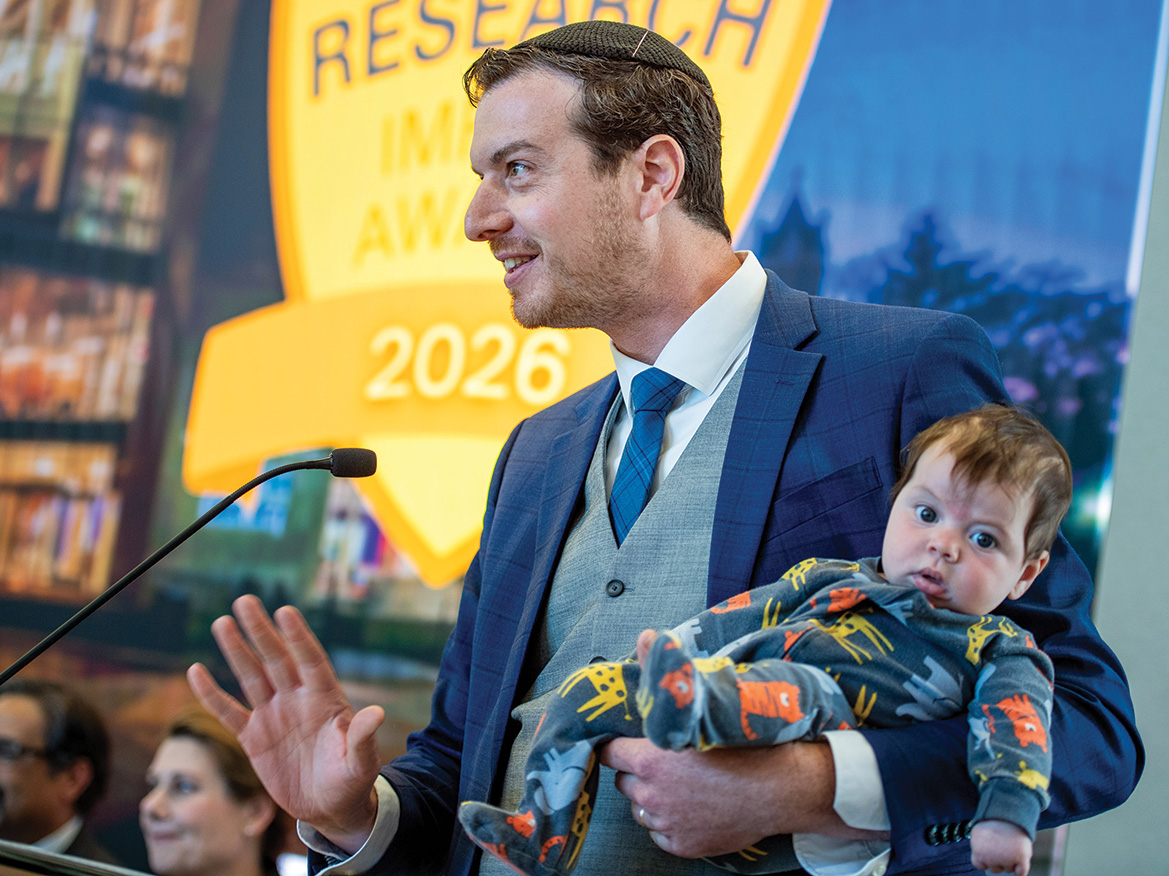A man holding a baby speaks into a microphone
