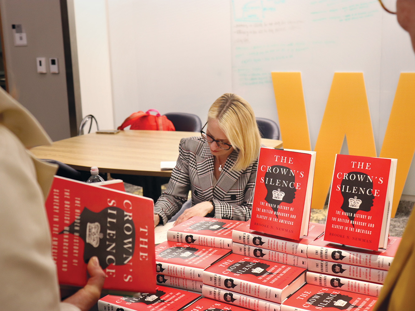 Brooke Newman signs a copy of her book, The Crown's Silence