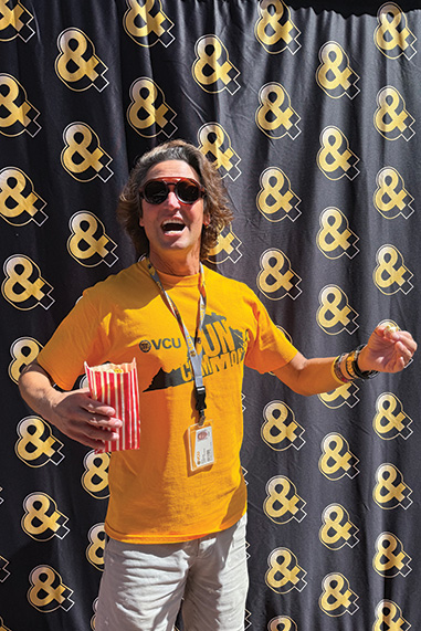 Kerry Klapperich poses in front of a black curtain with gold ampersands