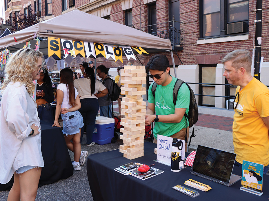 A student plays a game of Jenga at an outdoor block party