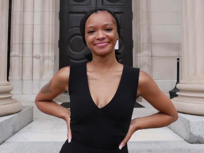 Queani Johnson stands with her hands on her hips between two columns outside of a buidling