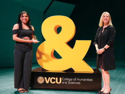 Student Kendra Diaz (left) and Dean Catherine Ingrassia stand next to an ampersand statue