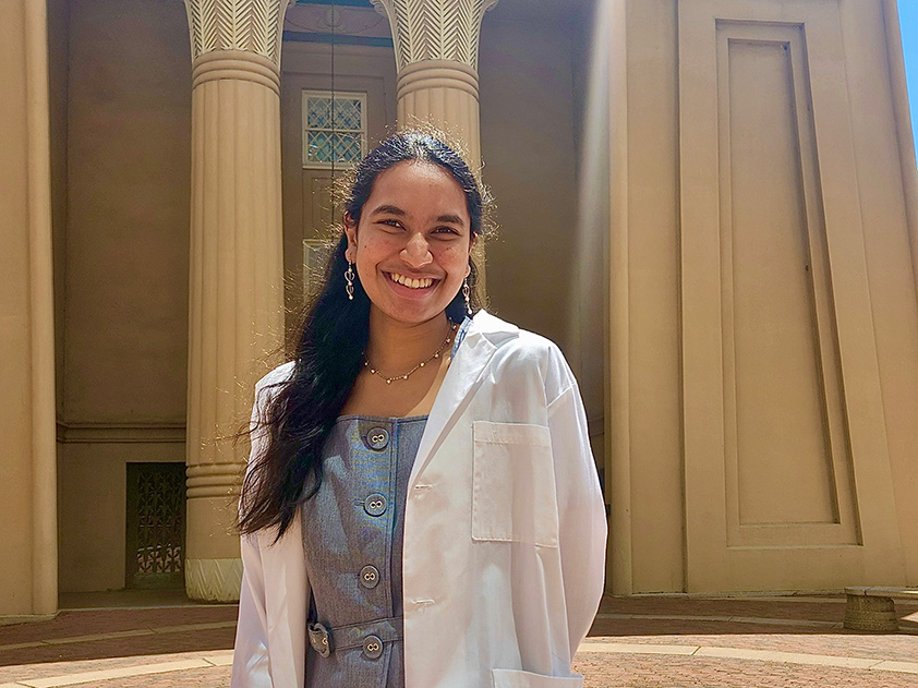 Alavala Vishnupriya stands in front of the Egyptian building in a white lab coat