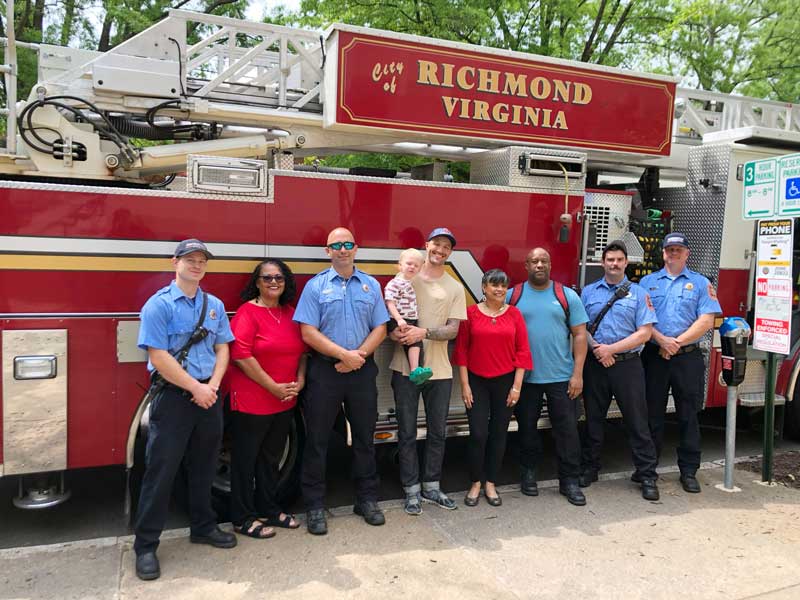 members of the college humanities and sciences community action council stand with richmond city firefighters in front of a firetruck