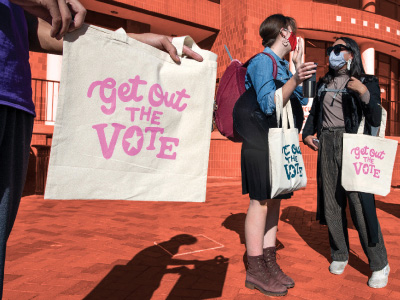 People standing outside of the VCU Student Commons building holding tote bags that say 