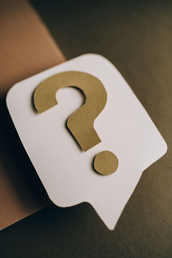 Tan question mark on a white speech bubble against a brown background