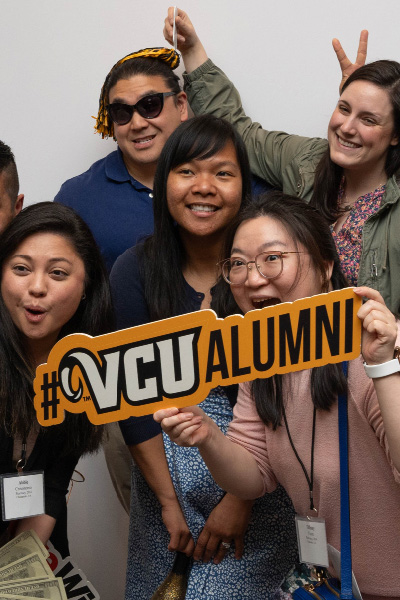 A group of students hold up a sign that reads #VCUalumni
