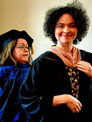 levi walter receiving assistance with their graduation regalia