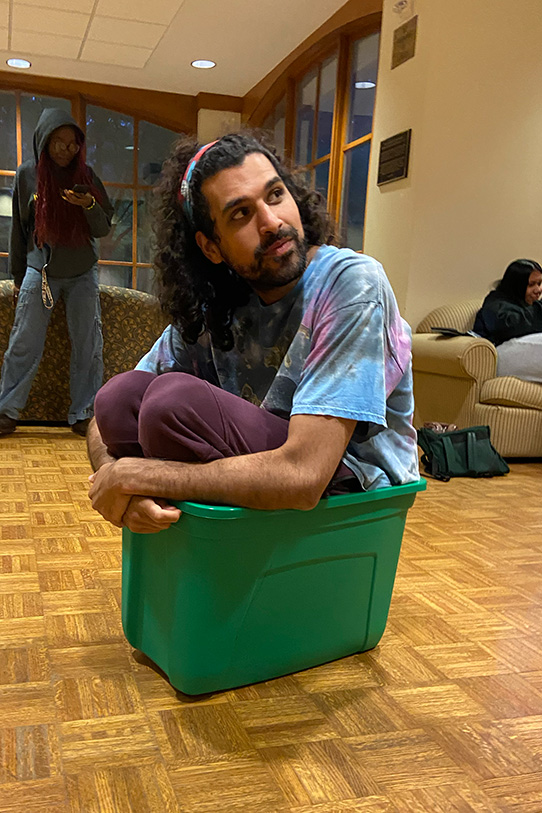 Rayan Ibrahim sits inside a green tote bin