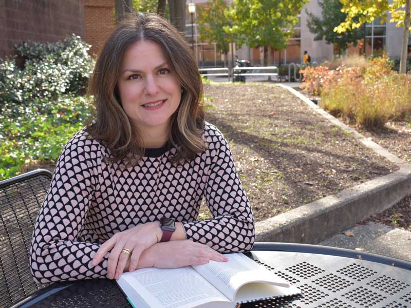 mary caton lingold reading a book at an outside table at v.c.u.