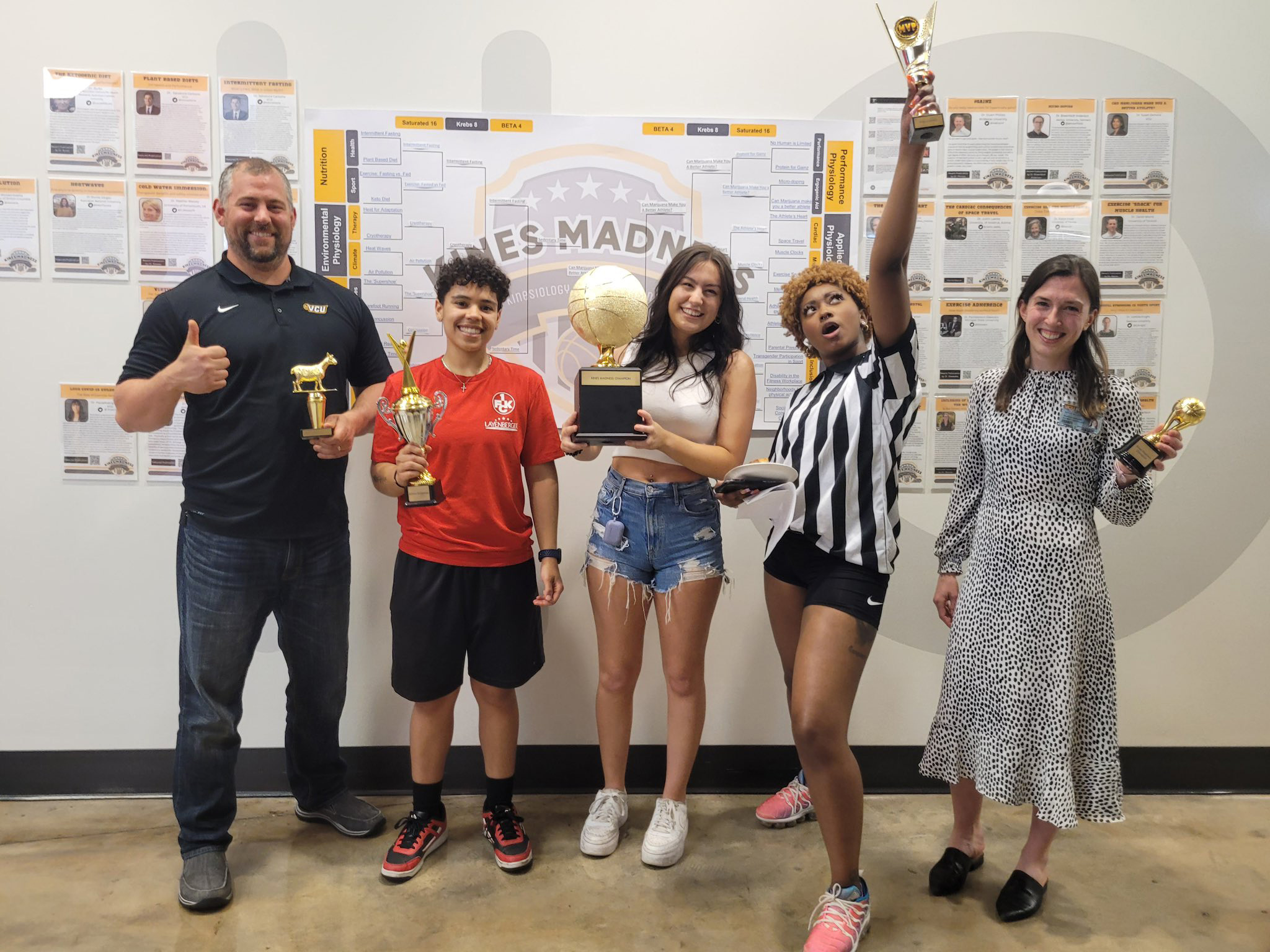 Four students and one faculty member holding up trophies