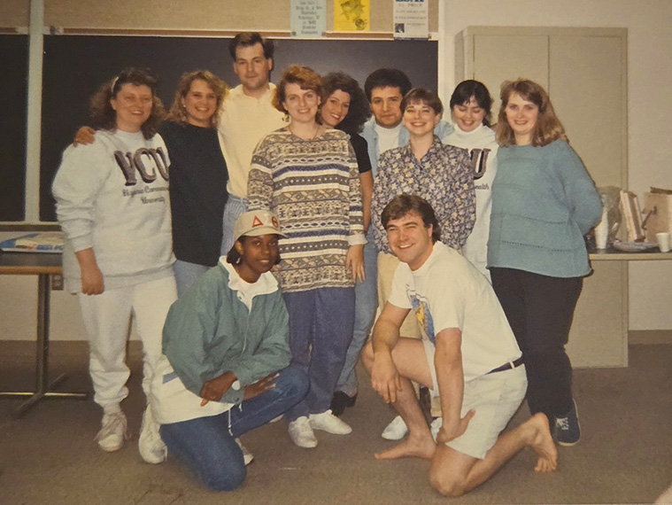 Adriene Marshal stands with a group of students in front of a classroom blackboard