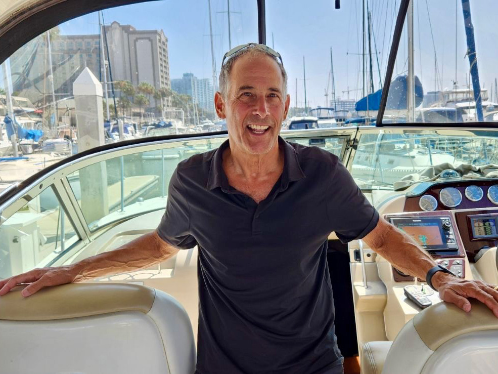 Peter Zucker stands on a boat with a marina in the background